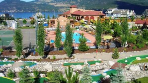 A residential area with a swimming pool, tennis courts, and a mountain backdrop. - Private Lake View Cottage with amenities for everyone! (Kelowna)