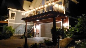 A two-story house with a covered porch and a garage. - Private Lake View Cottage with amenities for everyone! (Kelowna)