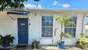 A house with a blue door, a window with blinds, and a potted plant in front. - Fisherman's Get-A-Way! Cozy waterfront retreat with access to Lake Okeechobee! (Okeechobee)