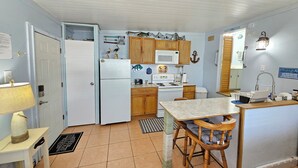A compact kitchen with white appliances, wooden cabinets, and a small dining area. - Fisherman's Get-A-Way! Cozy waterfront retreat with access to Lake Okeechobee! (Okeechobee)