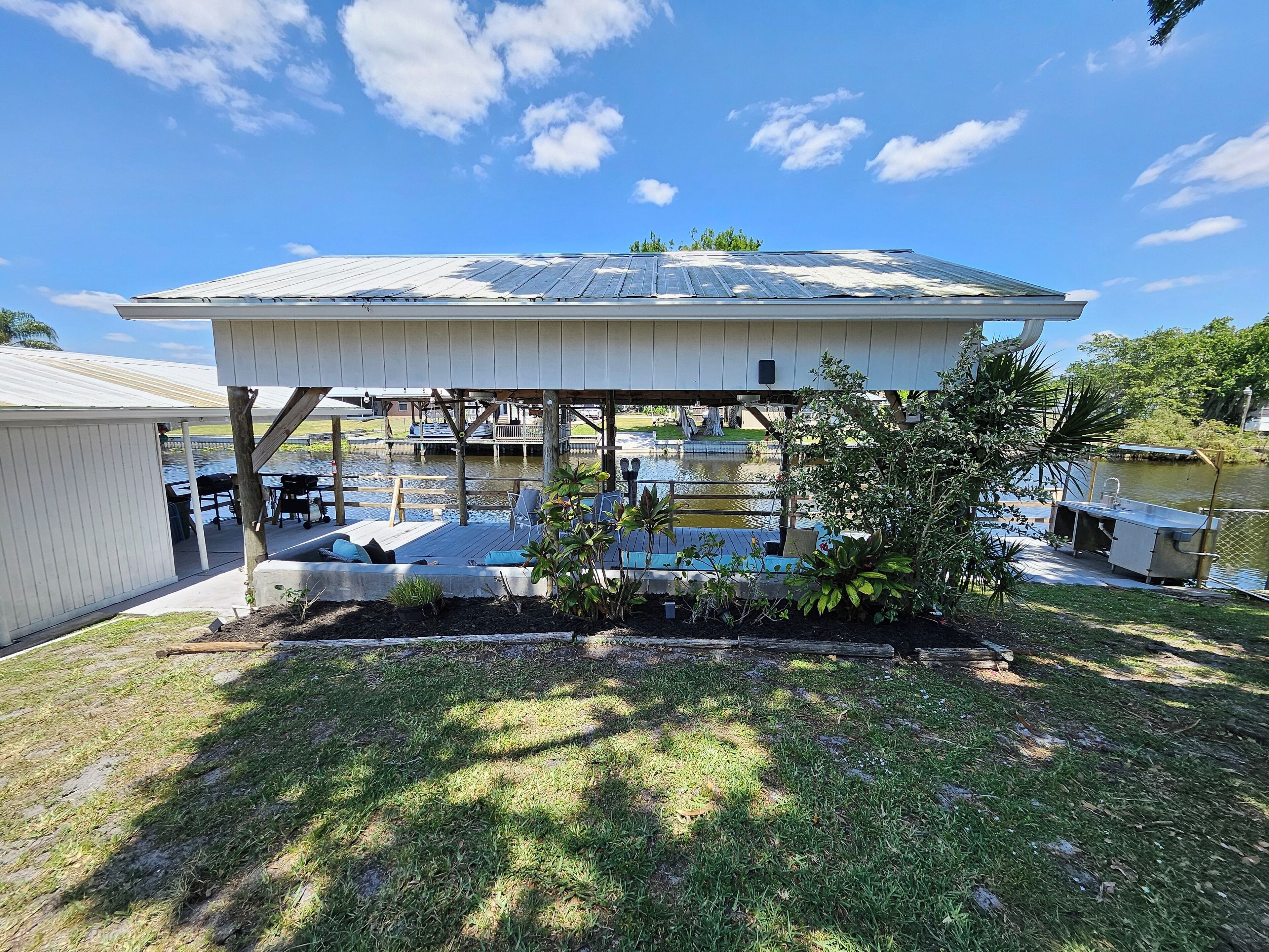 A covered outdoor area with a pool, deck chairs, and a small boat dock.