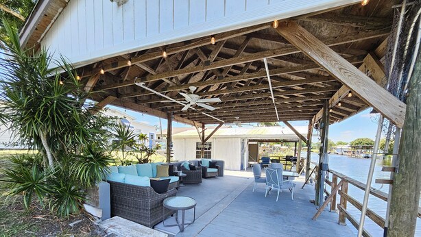 A covered outdoor seating area with wicker furniture and a ceiling fan. - Fisherman's Get-A-Way! Cozy waterfront retreat with access to Lake Okeechobee! (Okeechobee)