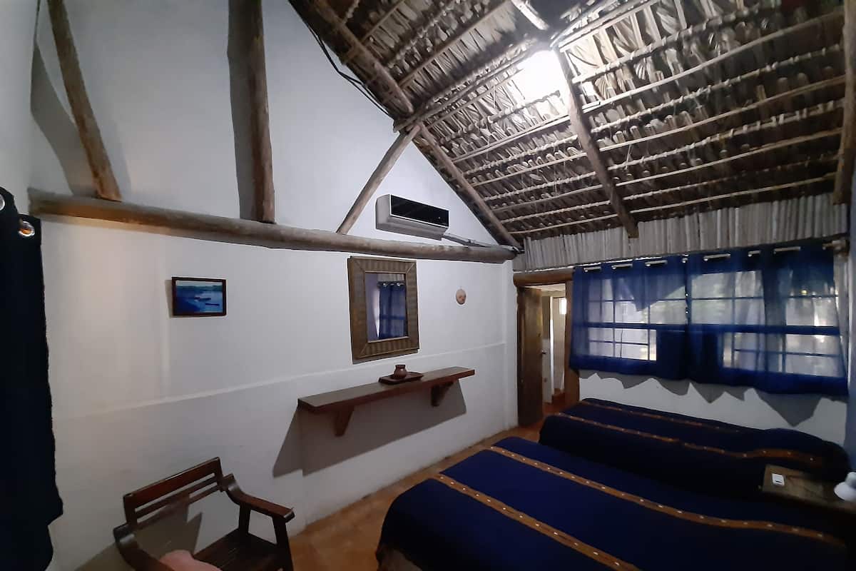 Ein Zimmer mit einem Bett, einem Sessel, einem Regal und einem Fenster mit Vorhängen.