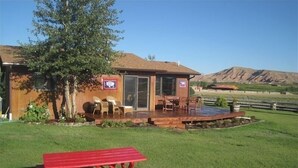 Una casa con un patio, una terraza de madera y una mesa de picnic.