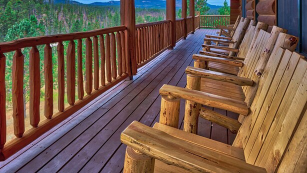A wooden deck with benches overlooking a forested landscape.