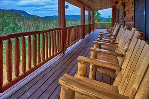 Une terrasse en bois avec des bancs donnant sur un paysage boisé.