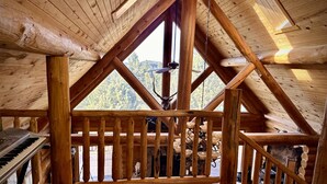 A wooden cabin with a sloped roof, a piano, a dog, and a fireplace.
