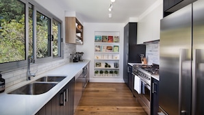 A modern kitchen with a large window, stainless steel appliances, and a white backsplash. - Maple View Medlow Bath, Blue Mountains (Medlow Bath)