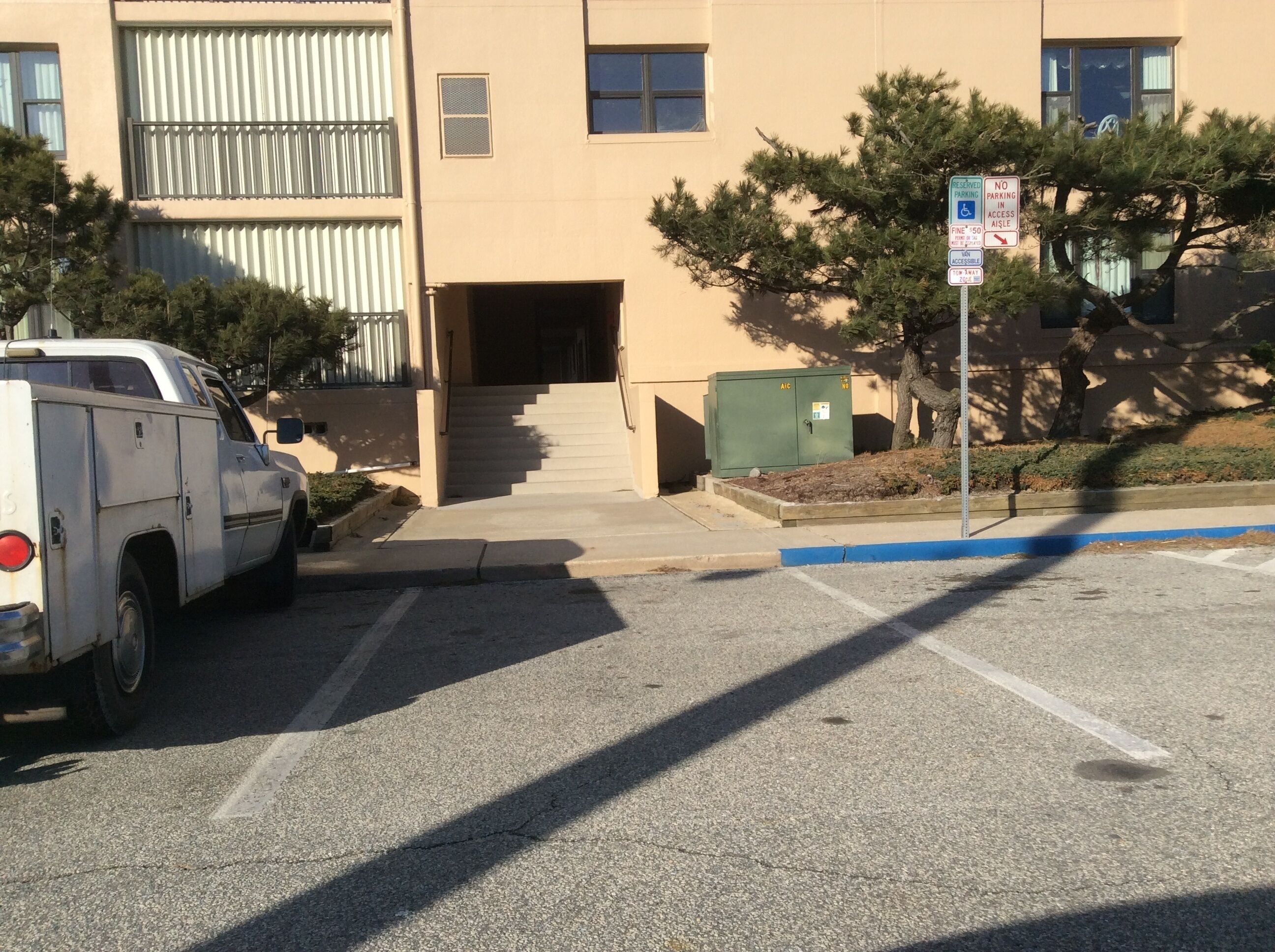 A building with a parking area, a staircase leading to an entrance, and a sign indicating no parking in access aisle.