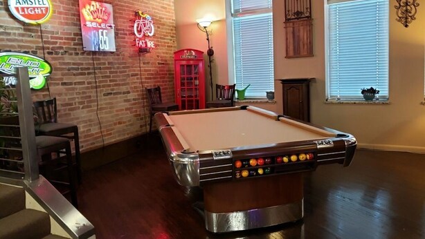A billiards table in a room with brick walls, neon signs, and a red telephone booth. - Up to 50% off for limited time! Professionally Cleaned, Pool & Foosball Table (Nashville)