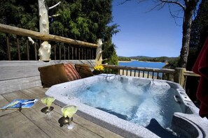 Un bain à remous sur une terrasse en bois, avec vue sur un lac.