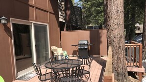 Una terrazza con un tavolo rotondo e sedie, un barbecue e una porta che dà su un'area coperta.