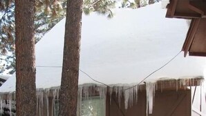Una casa con il tetto imbiancato dalla neve e stalattiti che pendono dai bordi.