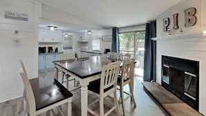 A modern kitchen with white cabinets, a dining table with chairs, and a fireplace with decorative letters. - Where Pool Days Steal the Show | 8 ppl | IC13 (Put-in-Bay)