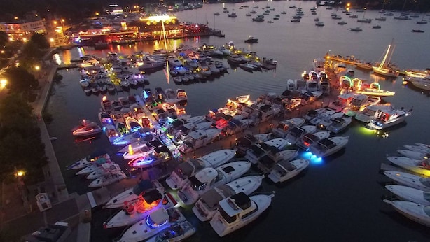 A marina with numerous boats docked, illuminated by colorful lights, and a large building with lights in the background. - Where Pool Days Steal the Show | 8 ppl | IC13 (Put-in-Bay)