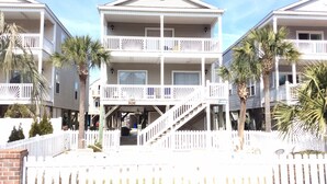 Un hôtel situé en bord de mer, avec une structure à deux étages, une véranda et un escalier menant à l’étage supérieur.
