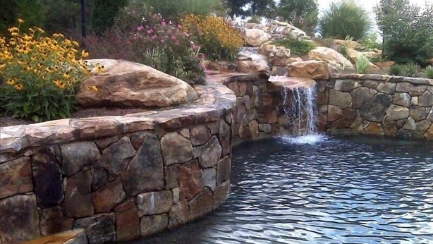 Ein angelegter Garten mit Teich, Steinmauern und einem Wasserfall.