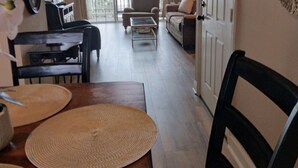 A spacious living room with a dining area, a staircase, and a large window providing natural light.