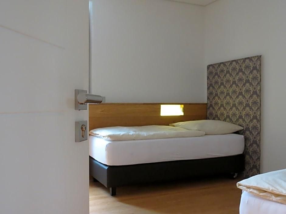 Ein Einzelbett mit Holz-Kopfteil, einer Wand mit Muster und einer Tür mit Griff.