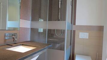 Ein Badezimmer mit Waschbecken, Spiegel, Dusche und Toilette.
