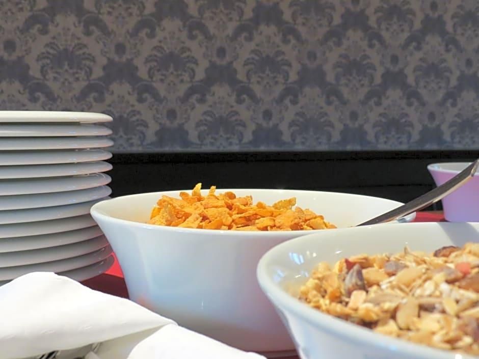 Ein Tisch mit Schüsseln Frühstücksflocken und einem Stapel Teller.
