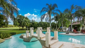 Una piscina con un puente, palmeras y un edificio de techo rojo.