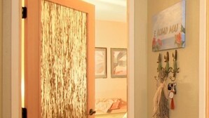 Un couloir avec une porte en bois, un sol en pierre et un mur orné d’une enseigne et d’œuvres d’art mural.