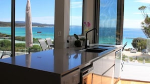 A modern kitchen with a large window overlooking a scenic coastal view.