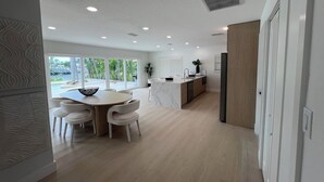 A modern kitchen with a central island, white cabinetry, and a view of a tropical outdoor area.