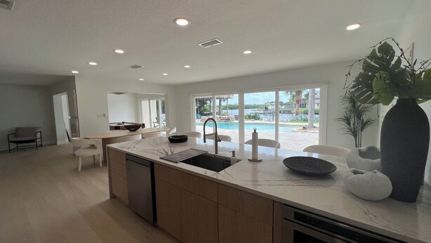 A modern kitchen with a large island, built-in appliances, and a view of a pool and outdoor area.