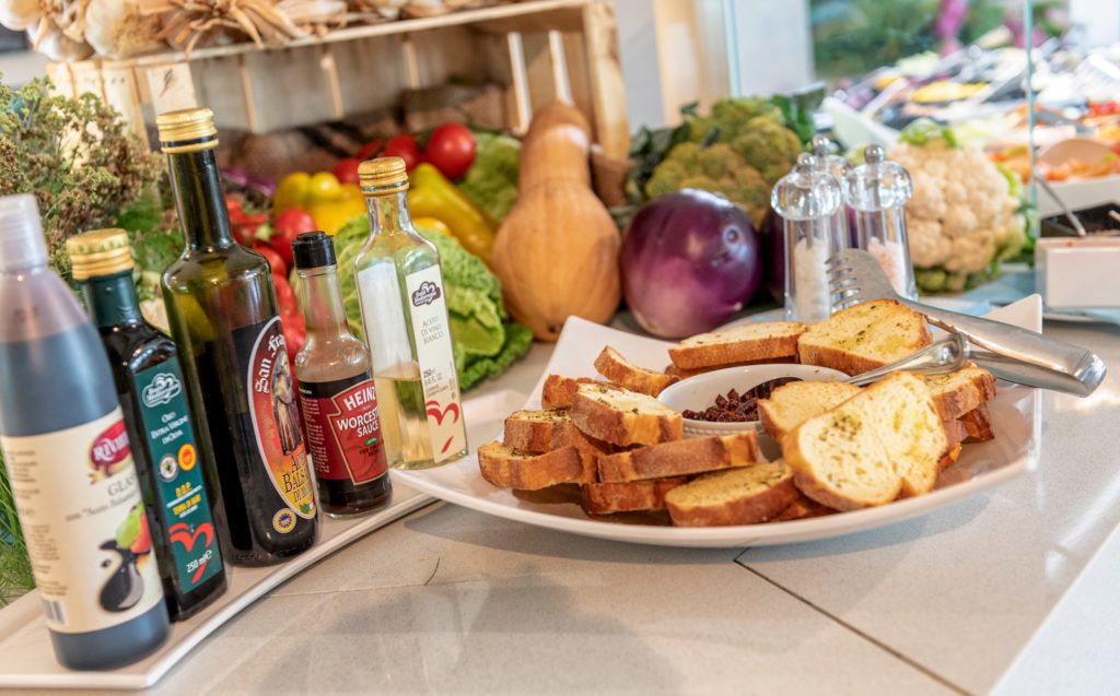 A table with various food items, including bread, vegetables, and condiments.