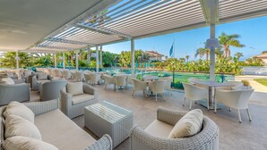 Un espacio de estar al aire libre con mobiliario de mimbre y vista a la piscina.