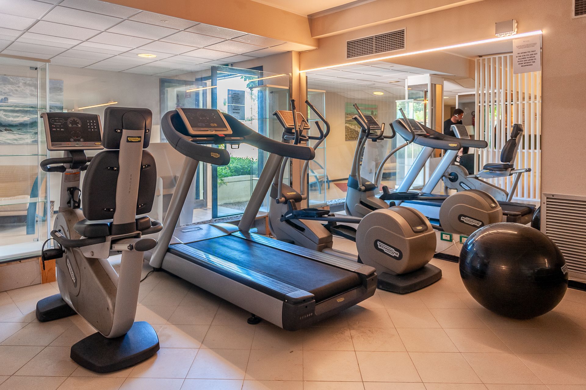 Een sportschool met loopbanden, een hometrainer en een grote fitnessbal.