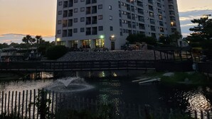 Um edifício alto com várias varandas e uma fonte espelhando a água em frente.