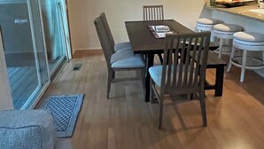 A dining area with a wooden table and chairs, a chandelier, and a view through a sliding glass door. - Beautiful Townhome Near Glacier Park!! (Columbia Falls)