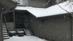 A snow-covered backyard with a staircase leading to a covered porch. - Beautiful Townhome Near Glacier Park!! (Columbia Falls)