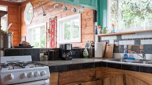 Una cocina con gabinetes de madera, estufa, cafetera y fregadero.