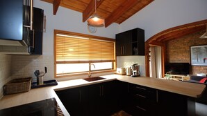 Una cucina moderna con un'isola grande, travi in legno a soffitto e un muro in mattoni.