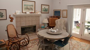 A dining area with a round table, chairs, a fireplace, and framed artwork on the walls. - Relax by the Sea! Wide Beach! Beautiful view from porch. (Fripp Island)