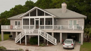 A two-story house with a covered porch, a staircase, and a garage. - Relax by the Sea! Wide Beach! Beautiful view from porch. (Fripp Island)
