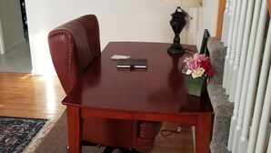 Une table de salle à manger en bois, agrémentée d’une lampe noire et d’un petit arrangement floral.