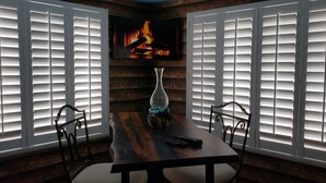 A dining area with a wooden table, chairs, a vase, and a fireplace.
