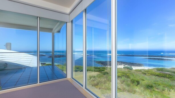 Una habitación moderna con amplios ventanales que ofrecen vistas a un paisaje costero.
