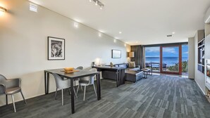 Ein modernes Hotelzimmer mit Essbereich, einer Couch und Blick auf den Ozean.