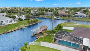 A residential area with a canal, houses, and a swimming pool. - Fully stocked & Pet Friendly! Bikes, pool table, hot tub & more! Villa Aleena - SWFL Rentals (Cape Coral)