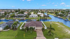 A residential area with houses, a canal, and a swimming pool. - Fully stocked & Pet Friendly! Bikes, pool table, hot tub & more! Villa Aleena - SWFL Rentals (Cape Coral)