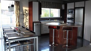 A modern kitchen with a central island, bar stools, a dishwasher, and a window with curtains. - Relax in the Wanganui Dunes (Wanganui Township)