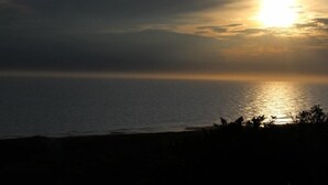 A sunset over the ocean with a beach in the foreground. - Relax in the Wanganui Dunes (Wanganui Township)