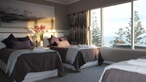 A hotel room with two beds, a large window with a view of trees, and a painting on the wall. - Relax in the Wanganui Dunes (Wanganui Township)