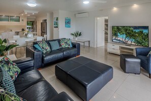 Een moderne woonkamer met een bank, een poef en een flatscreen televisie.